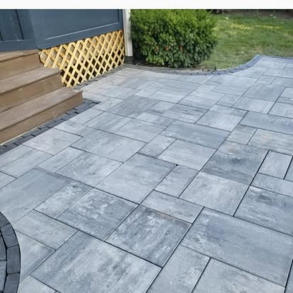 A gray Unilock paver patio laid beside a wood deck.