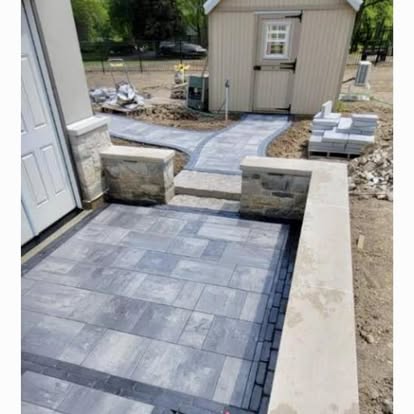 A paver patio with a stone-veneer seat wall and pillars.